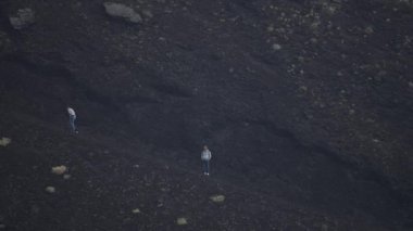 Erkek ve kadın turistler Etna Dağı 'ndaki kraterde yürüyüş yapıyorlar. Arka planda dumanla kaplanmış volkanik manzaranın görüntüsü. Erkekler ve kadınlar popüler eğlence için maceralı bir tatil yapıyorlar..