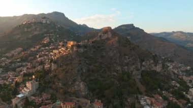 Sicilya, Taormina 'daki Antik Yunan Tiyatrosu' nun kalıntılarının havadan görünüşü İyon Denizi 'nin Giardini-Naxos körfezine sabah güneşi altında uzanan Etna' nın dumanlı kuyruğuyla yayılıyor..