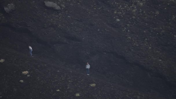 エトナ山の火口を歩く男性と女性の観光客 背景に煙に覆われた空と火山の風景の眺め 男性と女性は人気のアトラクションで冒険的な休暇を楽しんで — ストック動画