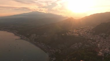 Sicilya, Taormina 'daki Antik Yunan Tiyatrosu' nun kalıntılarının havadan görünüşü İyon Denizi 'nin Giardini-Naxos körfezine sabah güneşi altında uzanan Etna' nın dumanlı kuyruğuyla yayılıyor..
