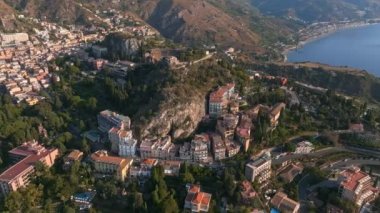 Sicilya, Taormina 'daki Antik Yunan Tiyatrosu' nun kalıntılarının havadan görünüşü İyon Denizi 'nin Giardini-Naxos körfezine sabah güneşi altında uzanan Etna' nın dumanlı kuyruğuyla yayılıyor..