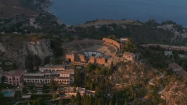 Sicilya, Taormina 'daki Antik Yunan Tiyatrosu' nun kalıntılarının havadan görünüşü İyon Denizi 'nin Giardini-Naxos körfezine sabah güneşi altında uzanan Etna' nın dumanlı kuyruğuyla yayılıyor..