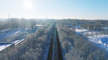 Karla kaplı ağaçların ve batan güneşin sıcacık parıltısıyla aydınlanan donmuş toprakların kış harikalar diyarı. Donmuş yolun kış günündeki görüntüsü. Sihirli bir kış sahnesi.