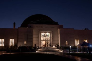 Los Angeles, ABD. 20 Eylül 2022. Aydınlatılmış Griffith Gözlemevi 'nin gece vakti Los Angeles Havzası' na bakan tabela ve giriş kapısı ve arka planda mavi gökyüzü manzarası