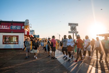 Los Angeles, ABD. 20 Eylül 2022. Santa Monica 66 'nın yanından geçen çok ırklı insanlar iskele ve açık gökyüzü üzerinde gün batımında parlak güneşle birlikte yürüyorlar.