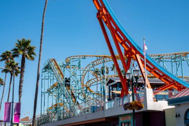 Santa Cruz, ABD. 20 Eylül 2022. Santa Cruz sahil şeridinde yaz boyunca arka planda açık mavi gökyüzü olan çeşitli lunapark gezileri ve palmiye ağaçlarının alçak açılı görüntüsü