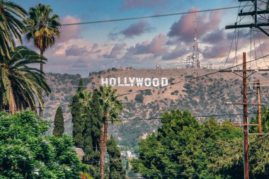 Los Angeles, ABD. 20 Eylül 2022. Güneşli bir günde elektrik direği ve ağaçların arasından görülebilen güzel Lee Dağı 'ndaki Hollywood tabelasının arka planında bulutlu bir gökyüzü var.
