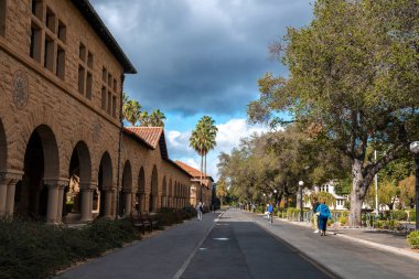 Palo Alto, ABD. 20 Eylül 2022. Tarihsel Stanford Üniversitesi ve Kaliforniya 'da bulutlu gökyüzünün altında büyüyen ağaçların sokak perspektifi azalıyor