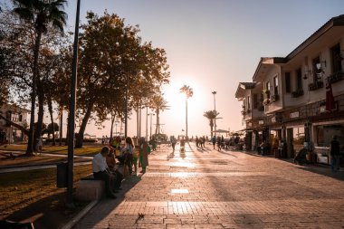 Yana, Hindi. 10 Ekim 2022. Erkek ve kadın turistler, gün batımında açık gökyüzünde parlayan güneşle birlikte şehri keşfediyorlar.