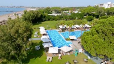 Lüks tropik otel tatil köyü. Açık hava turizmi. Yüzme havuzu, plaj sandalyeleri ve palmiye ağaçları olan lüks bir tatil köyü. Yaz adası seyahati ve cennet tatili