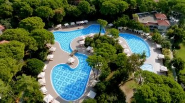 Lüks tropik otel tatil köyü. Açık hava turizmi. Yüzme havuzu, plaj sandalyeleri ve palmiye ağaçları olan lüks bir tatil köyü. Yaz adası seyahati ve cennet tatili