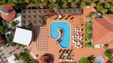 Lüks tropik otel tatil köyü. Açık hava turizmi. Yüzme havuzu, plaj sandalyeleri ve palmiye ağaçları olan lüks bir tatil köyü. Yaz adası seyahati ve cennet tatili