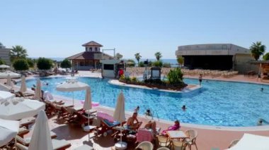 Lüks tropik otel tatil köyü. Açık hava turizmi. Yüzme havuzu, plaj sandalyeleri ve palmiye ağaçları olan lüks bir tatil köyü. Yaz adası seyahati ve cennet tatili