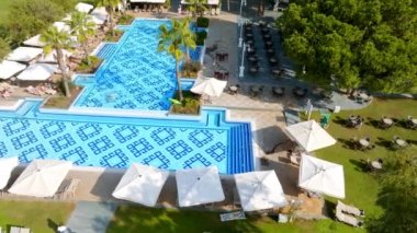Lüks tropik otel tatil köyü. Açık hava turizmi. Yüzme havuzu, plaj sandalyeleri ve palmiye ağaçları olan lüks bir tatil köyü. Yaz adası seyahati ve cennet tatili