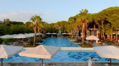 Lüks tropik otel tatil köyü. Açık hava turizmi. Yüzme havuzu, plaj sandalyeleri ve palmiye ağaçları olan lüks bir tatil köyü. Yaz adası seyahati ve cennet tatili