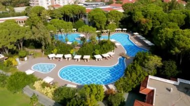 Lüks tropik otel tatil köyü. Açık hava turizmi. Yüzme havuzu, plaj sandalyeleri ve palmiye ağaçları olan lüks bir tatil köyü. Yaz adası seyahati ve cennet tatili