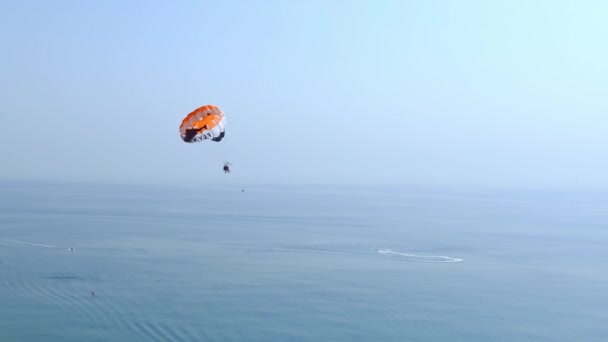 阳伞的场景视频 积极的娱乐形式 一个人被用长绳固定在移动的小船上 并且有特殊的降落伞在空中盘旋 — 图库视频影像