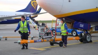 Sarı ceketli işçi Londra 'da Stansted Havaalanı' nda Ryanair uçağında çalışıyor ve bakımını yapıyor..