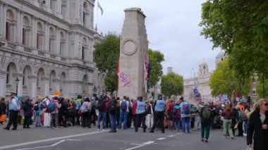 Polis caddelerden geçerken Londra sokaklarında büyük protestocular var. İnsanlar büyük protesto işaretleriyle çitlere tırmanıyor..