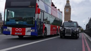 Londra 'daki Big Ben saat kulesinin yakınındaki Westminster Köprüsü trafiğinin görüntüsü. İkonik siyah taksiler ve kırmızı çift katlı otobüsler köprüden geçer. Londra 'nın Sembolü.