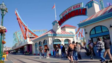 Beautiful summer day in Santa Cruz. People enjoying amusement park at Santa Cruz and Beach Boardwalk with clear blue sky in the background.