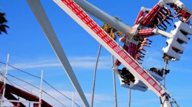 Beautiful summer day in Santa Cruz. People enjoying amusement park at Santa Cruz and Beach Boardwalk with clear blue sky in the background.