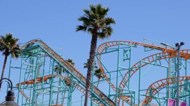 Beautiful summer day in Santa Cruz. People enjoying amusement park at Santa Cruz and Beach Boardwalk with clear blue sky in the background.