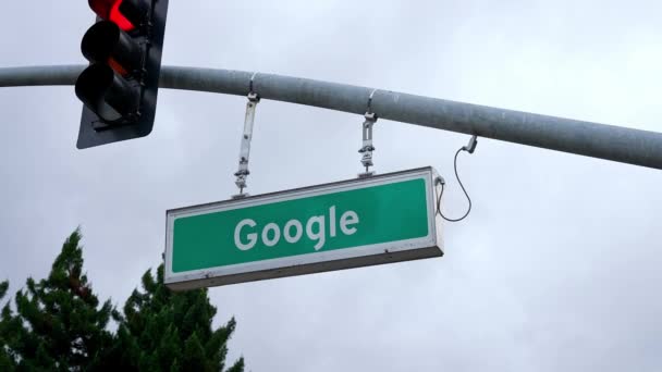 雲の多い空の下の極の交通信号によってぶら下がっている看板上のグーグルのテキスト Googleストリートサイン — ストック動画