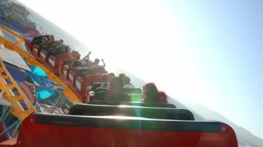 Ferris wheel and roller coaster rides and people exploring shops at the Pacific amusement park on the Santa Monica Pier.