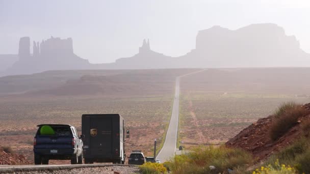 モニュメントバレーの高速道路でバイクに乗るバイカー 砂漠の風景の中 道路上を移動する車両 アメリカのロードトリップの概念 — ストック動画
