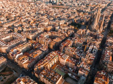 Aerial view of Barcelona City Skyline and Sagrada Familia Cathedral at sunset. Eixample residential famous urban grid. Cityscape with typical urban octagon blocks