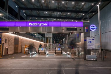 Entrance with Paddington text on purple metallic structure and empty escalators at underground subway station in London