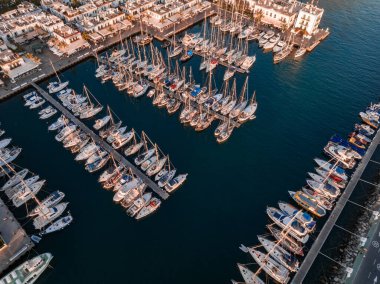 Luxury yachts docked by the golden coast of Spain during magical sunset lights. Luxury holiday concept. Aerial view.