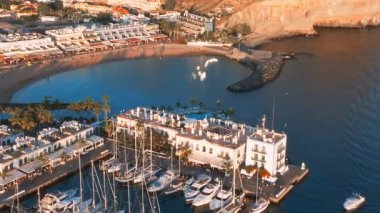 Luxury yachts docked by the golden coast of Spain during magical sunset lights. Luxury holiday concept. Aerial view.