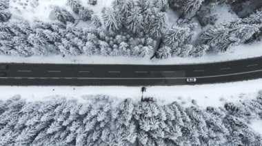 Forest in snow. Snowy forest road. Forest road from above. Aerial view of the winter curvy mountain road through the forest.