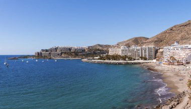 Su yüzeyinde yelkenli tekneleri ve Gran Canaria, İspanya 'da deniz kıyısında dağları olan binaları olan güzel bir deniz manzarası.