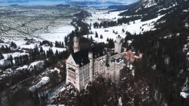 Bir kış günü Neuschwanstein Kalesi 'nin veya Schloss Neuschwanstein' in hava manzarası. Etrafı karla kaplı dağlar ve ağaçlarla çevrili..