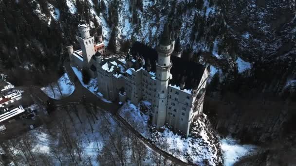 冬の日にはノイシュヴァンシュタイン城やシュロス ノイシュヴァンシュタインの空中風景が見られ 周りには雪に覆われた山々や木々が広がっています — ストック動画