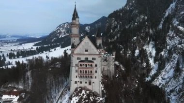 Bir kış günü Neuschwanstein Kalesi 'nin veya Schloss Neuschwanstein' in hava manzarası. Etrafı karla kaplı dağlar ve ağaçlarla çevrili..