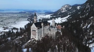 Bir kış günü Neuschwanstein Kalesi 'nin veya Schloss Neuschwanstein' in hava manzarası. Etrafı karla kaplı dağlar ve ağaçlarla çevrili..