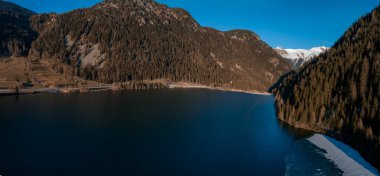 Göl kenarındaki ormanlı kayalık uçurumların havadan görünüşü. Dramatik ve resimli bir sahne. İsviçre Alpleri 'nde Bachalpsee, Grindelwald Vadisi, Bernese Oberland, Avrupa. Güzellik dünyası.