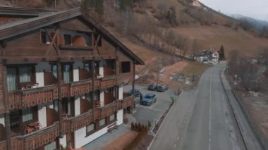 Bulutlu bir kış gününde, İtalya 'nın Tyrol kentinde, köyün ortasında çiçeklerle süslenmiş tipik ahşap bir dağ evi. Hava görünümü.