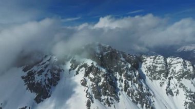 Tepeleri kar ve bulutlarla kaplı dağlık bir arazi. Ünlü St. Anton am Arlberg kayak merkezindeki dağların zirvelerini kaplayan sihirli bulutlar.