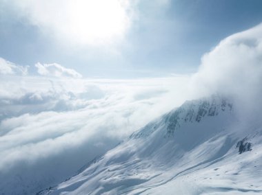 Tepeleri kar ve bulutlarla kaplı dağlık bir arazi. Ünlü St. Anton am Arlberg kayak merkezindeki dağların zirvelerini kaplayan sihirli bulutlar.