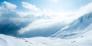 Tepeleri kar ve bulutlarla kaplı dağlık bir arazi. Ünlü St. Anton am Arlberg kayak merkezindeki dağların zirvelerini kaplayan sihirli bulutlar.
