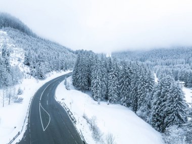 Forest in snow. Snowy forest road. Forest road from above. Aerial view of the winter curvy mountain road through the forest.