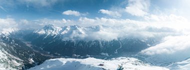 Tepeleri kar ve bulutlarla kaplı dağlık bir arazi. Ünlü St. Anton am Arlberg kayak merkezindeki dağların zirvelerini kaplayan sihirli bulutlar.