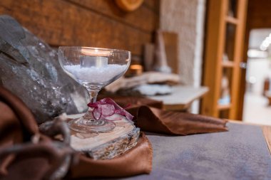 Otel odasındaki sehpanın üstündeki kuvars kristalinin şarap bardağında yanan çay lambasının yakın plan fotoğrafı.