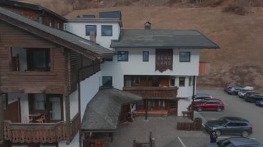 Bulutlu bir kış gününde, İtalya 'nın Tyrol kentinde, köyün ortasında çiçeklerle süslenmiş tipik ahşap bir dağ evi. Hava görünümü.