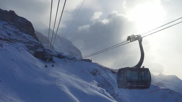 山頂と斜面の景色を望むスキーチェアリフト 青空と明るい太陽と雪の後の美しいスキー場 スキーヤーやスノーボーダーを運ぶスキーキャビン — ストック動画